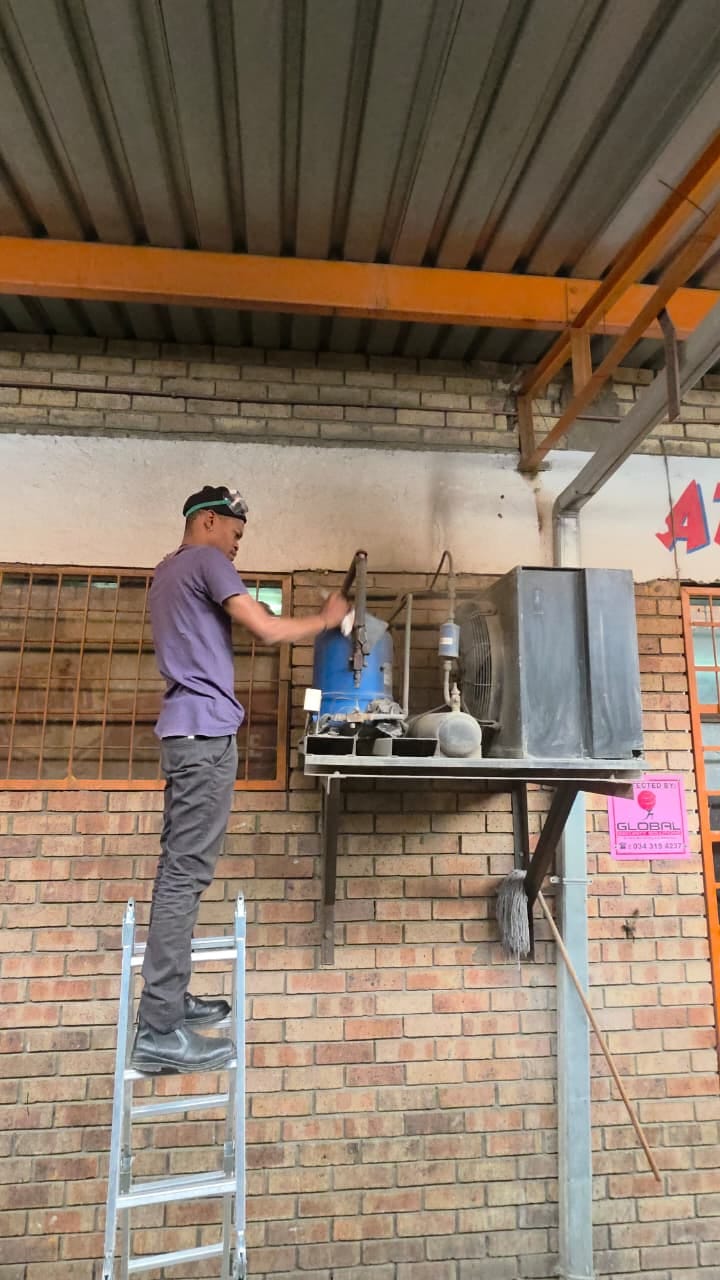 NOVA Cool technician servicing a commercial condensing unit mounted on a bracket