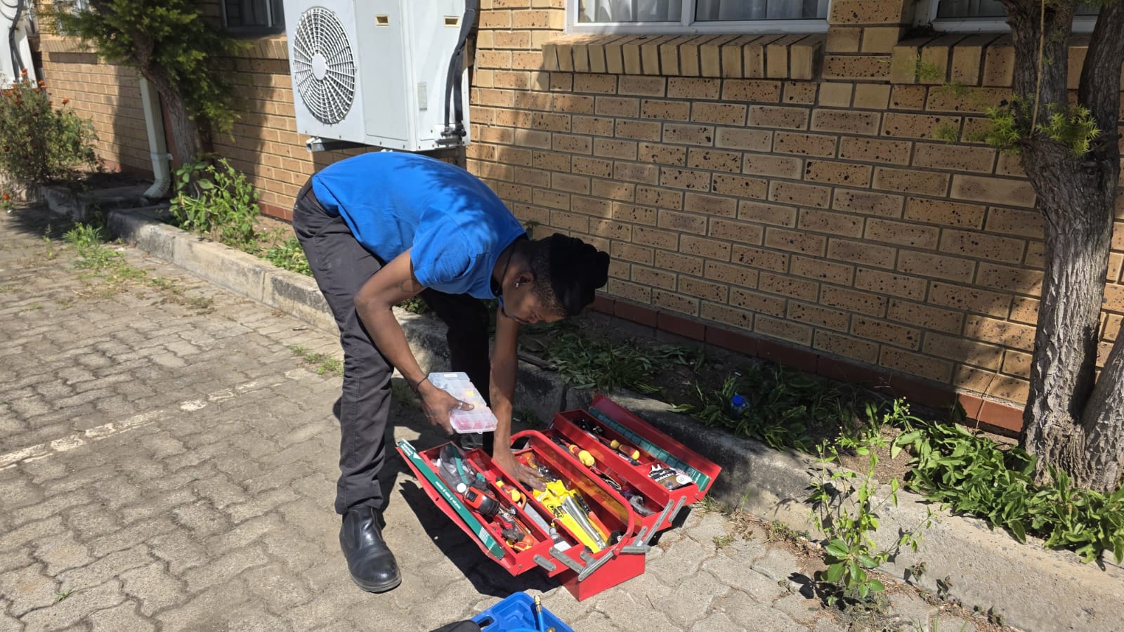 NOVA Cool technician preparing tools beside an outdoor air-conditioning unit