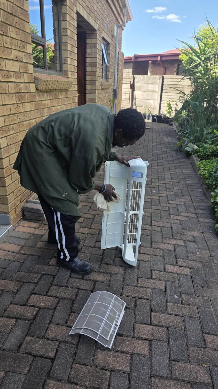 NOVA Cool technician cleaning an air-conditioner cover and filters outdoors