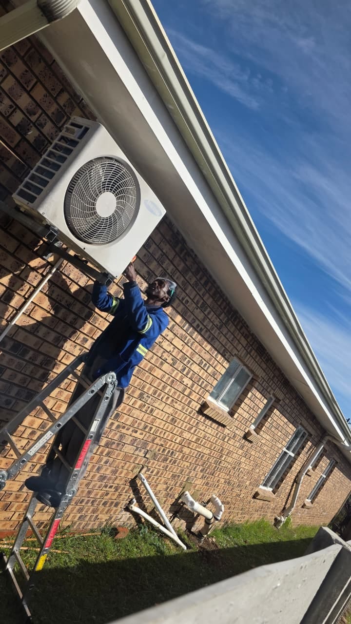 NOVA Cool technician installing an outdoor air-conditioning unit from a ladder