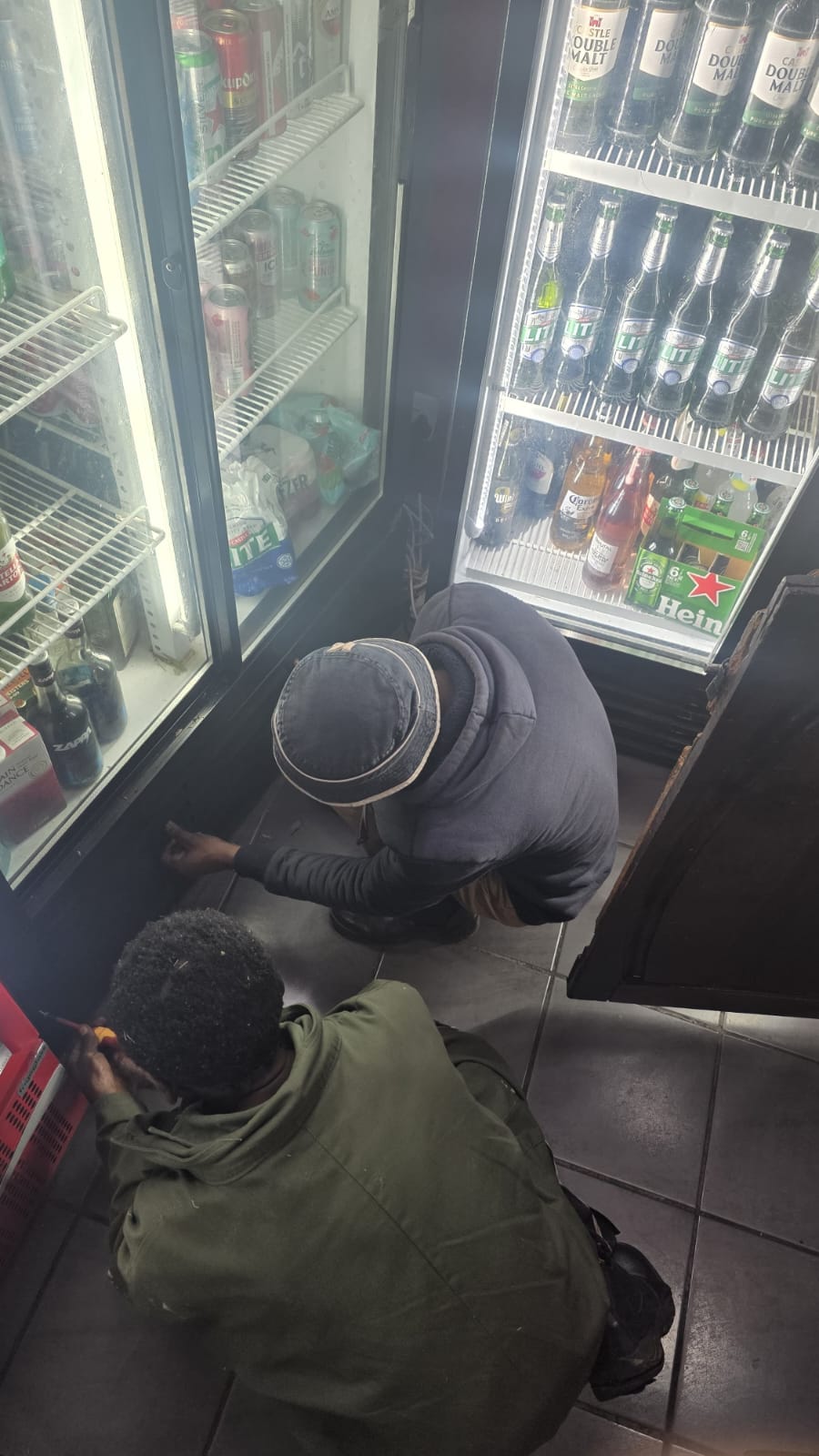 NOVA Cool technicians repairing a commercial beverage display fridge in a store
